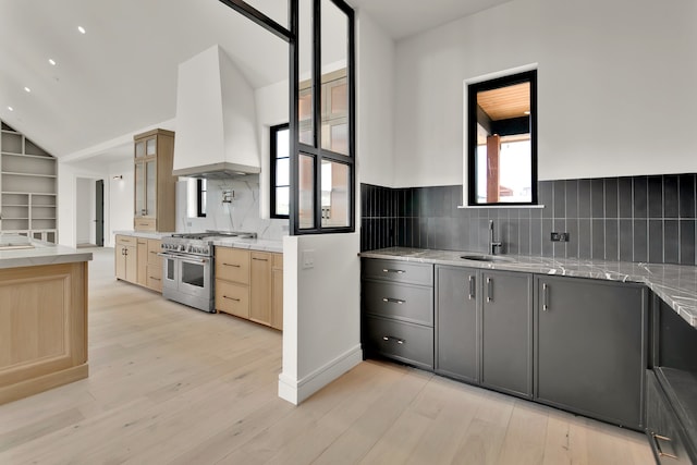 kitchen with light hardwood / wood-style floors, custom exhaust hood, light brown cabinetry, and double oven range