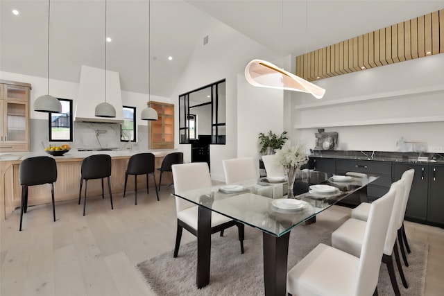 dining space featuring light hardwood / wood-style flooring and high vaulted ceiling