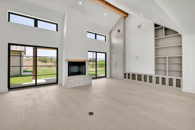 unfurnished living room with beamed ceiling, light hardwood / wood-style flooring, high vaulted ceiling, and plenty of natural light