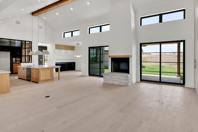 unfurnished living room featuring high vaulted ceiling, light wood-type flooring, beamed ceiling, and sink