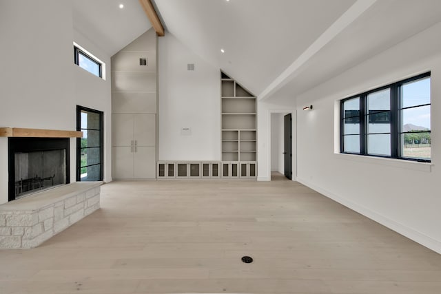 unfurnished living room with light hardwood / wood-style flooring, beam ceiling, and high vaulted ceiling