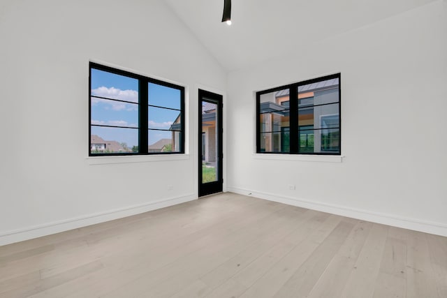 empty room featuring high vaulted ceiling, light wood-type flooring, ceiling fan, and a healthy amount of sunlight