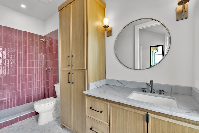 bathroom featuring a tile shower, tile patterned flooring, vanity, and toilet