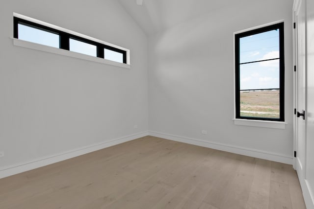 unfurnished room with light wood-type flooring and lofted ceiling