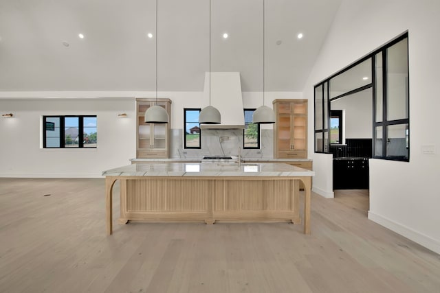 kitchen featuring high vaulted ceiling, light stone counters, hanging light fixtures, and a spacious island