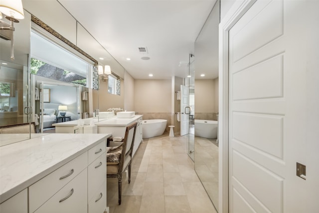 bathroom with a washtub, tile patterned floors, and vanity