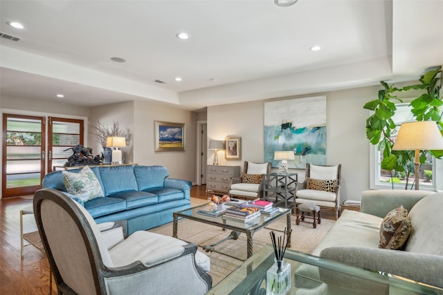 living room with hardwood / wood-style flooring, a raised ceiling, and french doors