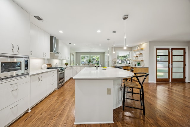 5332 Edmondson Ave, Dallas, TX 75209 - kitchen featuring appliances with stainless steel finishes, wall chimney exhaust hood, modern cabinets, a sink, and light countertops
