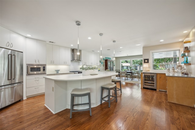 kitchen with white cabinetry, wood-type flooring, beverage cooler, stainless steel appliances, and a kitchen island