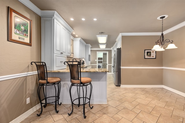 kitchen with crown molding, light tile patterned floors, stone countertops, white cabinetry, and decorative light fixtures