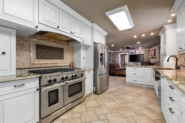 kitchen featuring stainless steel appliances, ceiling fan, sink, tasteful backsplash, and white cabinetry