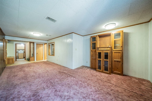 interior space with a textured ceiling, crown molding, and carpet flooring