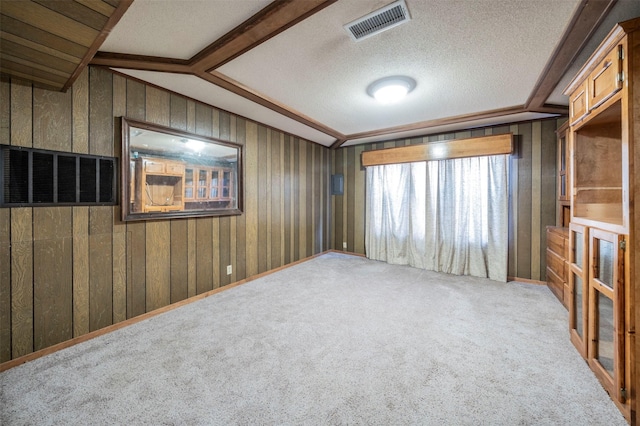 carpeted empty room featuring lofted ceiling with beams, a textured ceiling, and wooden walls