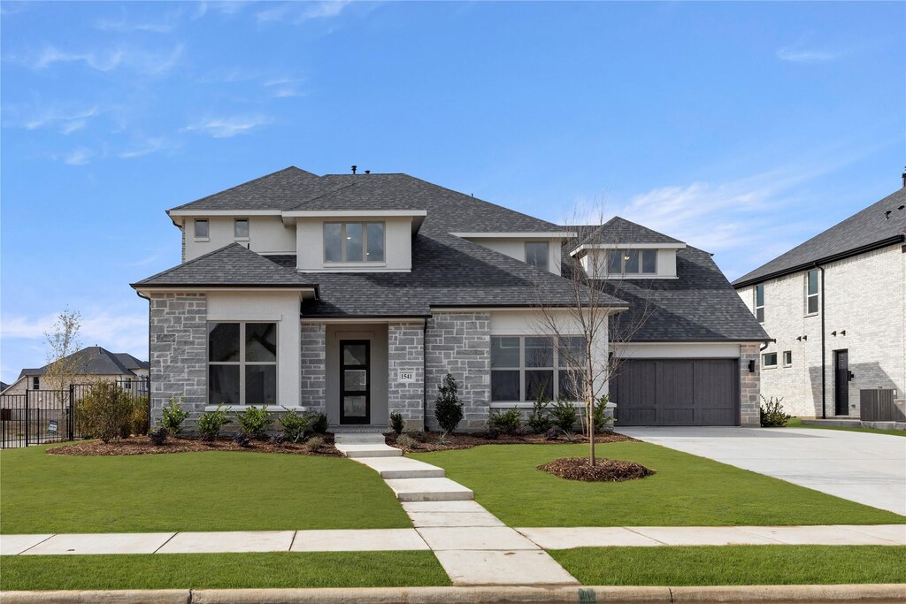 prairie-style home with a garage and a front lawn