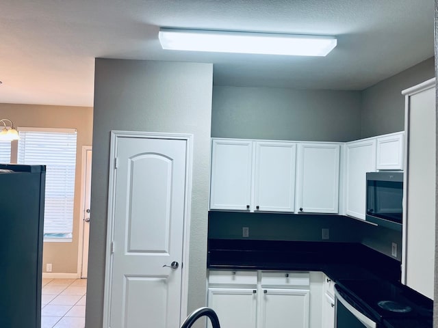 kitchen featuring stove, black fridge, a wealth of natural light, and light tile patterned floors