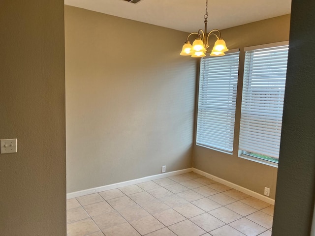 empty room with an inviting chandelier, a wealth of natural light, and light tile patterned floors