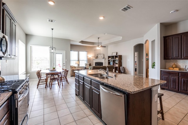 kitchen with a kitchen island with sink, sink, dark brown cabinets, and appliances with stainless steel finishes