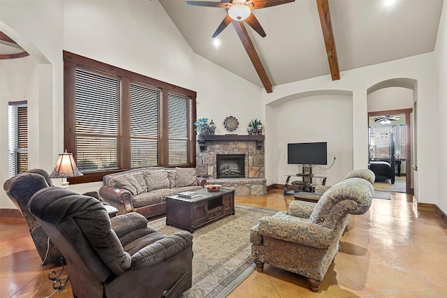 living room with beam ceiling, a stone fireplace, high vaulted ceiling, and ceiling fan