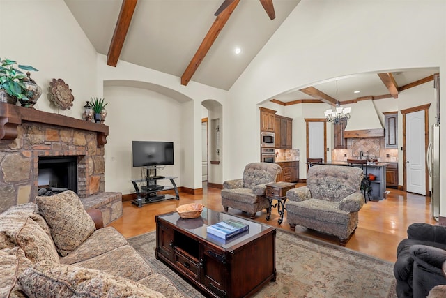 tiled living room featuring beamed ceiling, a stone fireplace, high vaulted ceiling, and an inviting chandelier