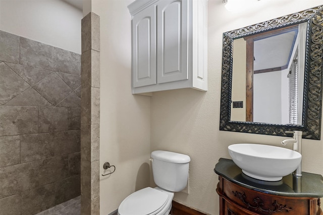 bathroom with vanity, toilet, and a tile shower