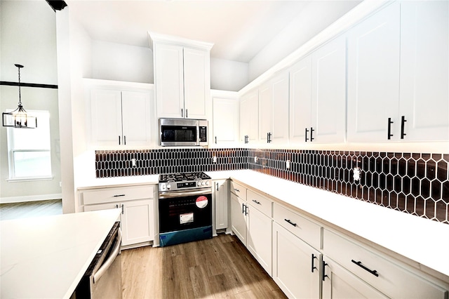 kitchen with dark wood-type flooring, decorative backsplash, appliances with stainless steel finishes, decorative light fixtures, and white cabinetry