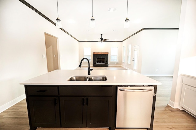 kitchen with pendant lighting, sink, crown molding, light hardwood / wood-style flooring, and stainless steel dishwasher