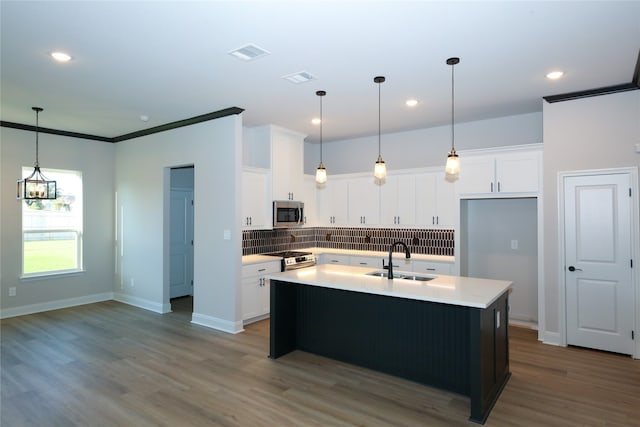 kitchen featuring white cabinetry, sink, decorative backsplash, and a center island with sink