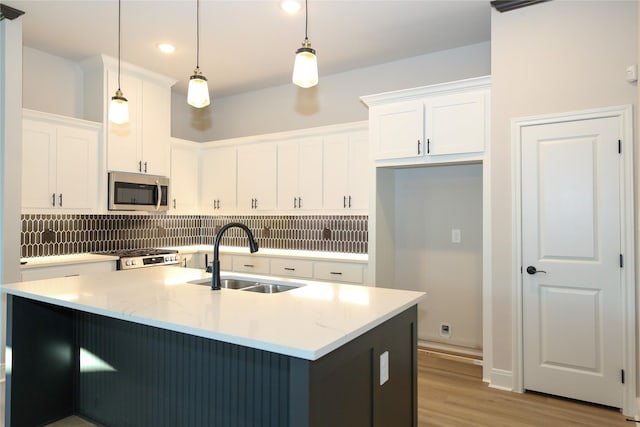 kitchen featuring pendant lighting, a kitchen island with sink, sink, appliances with stainless steel finishes, and white cabinetry