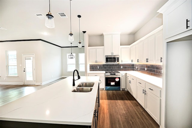 kitchen with sink, white cabinetry, a kitchen island with sink, stainless steel appliances, and decorative backsplash