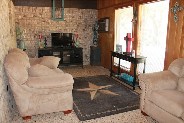 living area featuring wood walls, speckled floor, and brick wall