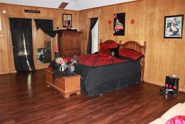 bedroom featuring wooden walls, baseboards, and wood finished floors