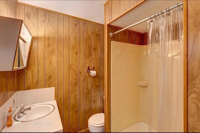 bathroom featuring toilet, a shower with curtain, wood walls, and vanity