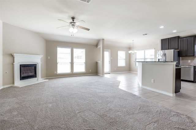 unfurnished living room with light colored carpet and ceiling fan with notable chandelier