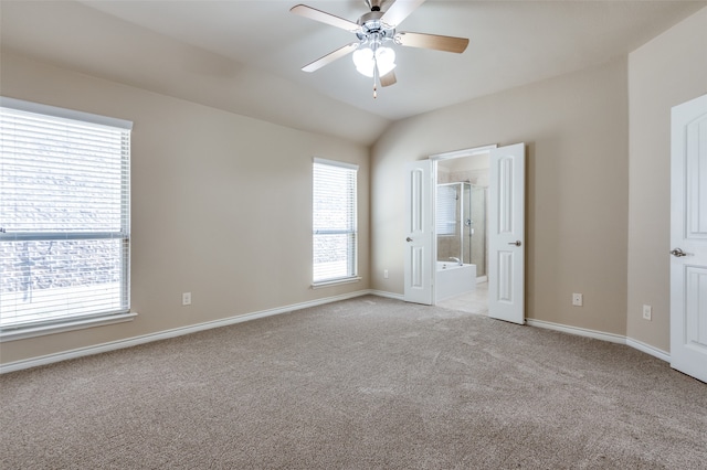 unfurnished bedroom with ceiling fan, light colored carpet, ensuite bathroom, and vaulted ceiling