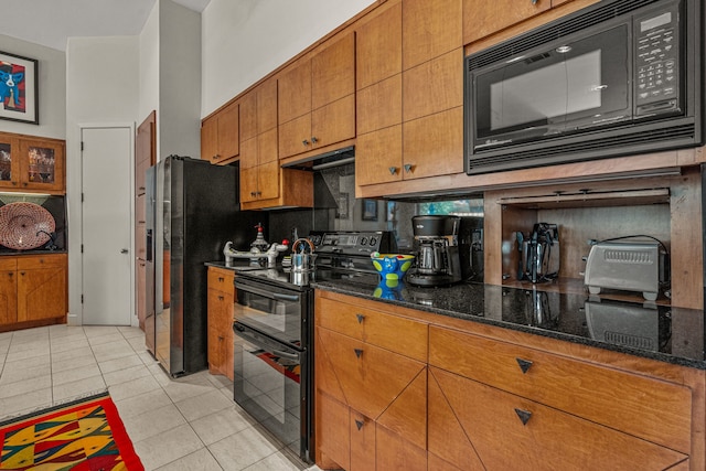 kitchen featuring dark stone counters, light tile patterned floors, black appliances, and tasteful backsplash