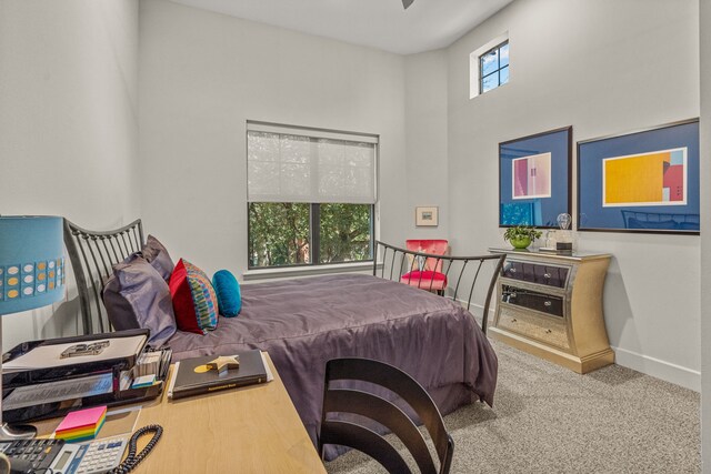 bedroom with multiple windows, a high ceiling, and carpet floors