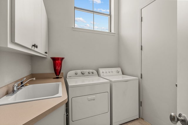 clothes washing area featuring washing machine and dryer, sink, and cabinets