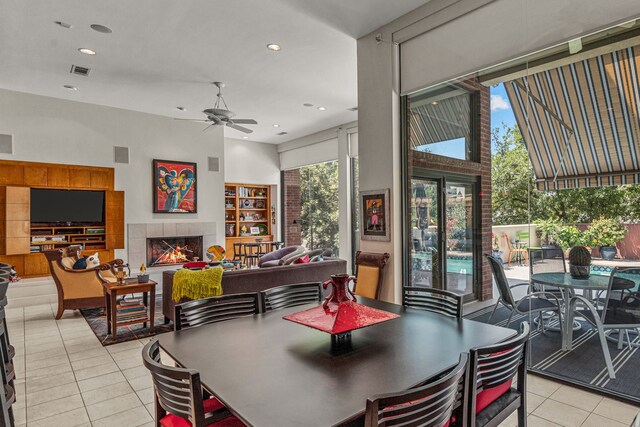 tiled dining area featuring a tile fireplace, ceiling fan, and a towering ceiling