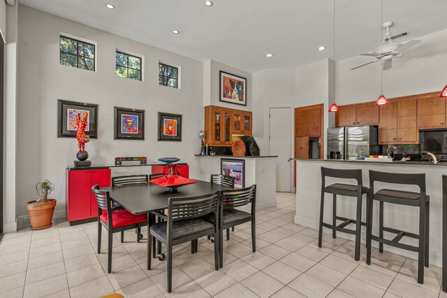 dining area featuring light tile patterned floors, a towering ceiling, and ceiling fan