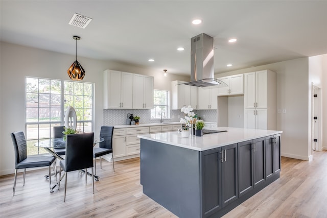 kitchen featuring a kitchen island, white cabinets, and island range hood