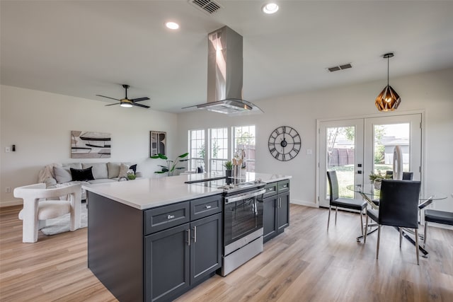 kitchen featuring stainless steel electric range oven, island range hood, a healthy amount of sunlight, and light wood-type flooring