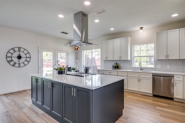 kitchen with tasteful backsplash, gray cabinetry, island range hood, stainless steel dishwasher, and light wood-type flooring