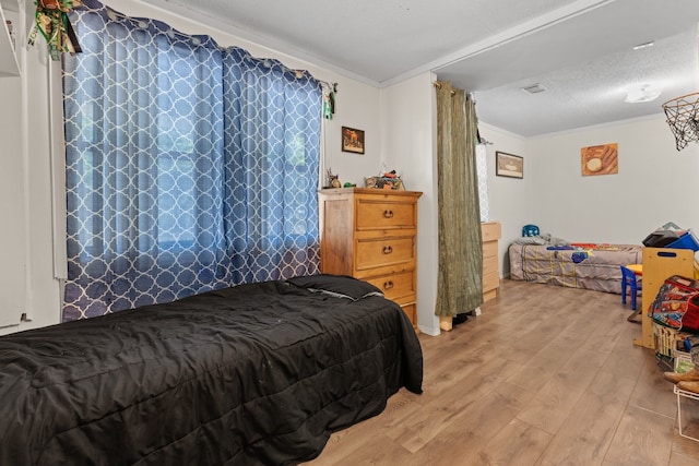 bedroom featuring crown molding, a textured ceiling, and hardwood / wood-style floors