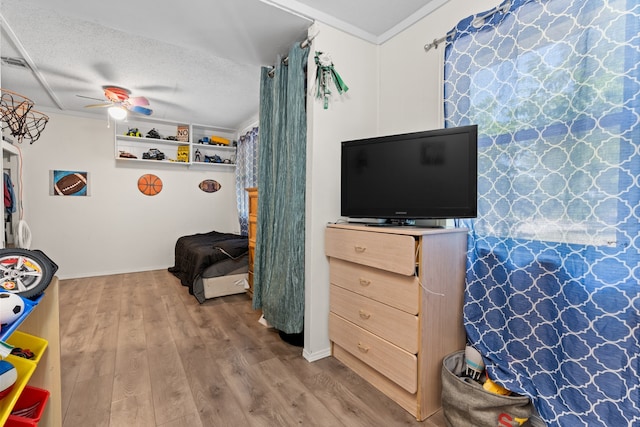 recreation room featuring crown molding, a textured ceiling, ceiling fan, and wood-type flooring