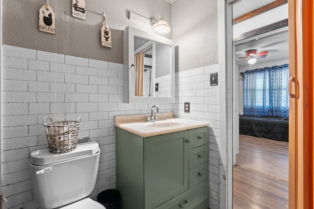 bathroom featuring brick wall, toilet, hardwood / wood-style floors, and vanity