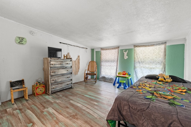 bedroom featuring ornamental molding, a textured ceiling, and hardwood / wood-style flooring