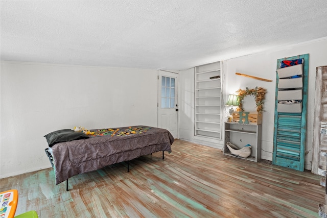 bedroom with ornamental molding, a textured ceiling, and hardwood / wood-style flooring