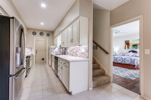 kitchen featuring stainless steel appliances, light hardwood / wood-style floors, ornamental molding, ceiling fan, and white cabinets