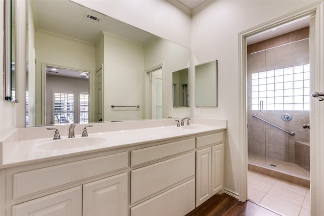 bathroom with vanity, tile patterned flooring, a tile shower, and crown molding