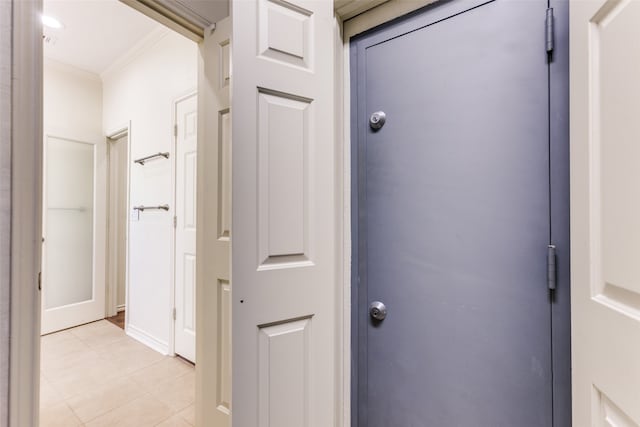 hall featuring light tile patterned floors and crown molding